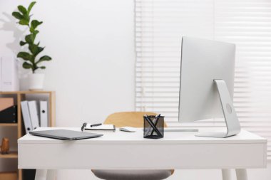 Ofisteki beyaz masa üzerinde modern bilgisayar, dizüstü bilgisayar ve kırtasiye ile şık bir iş yeri