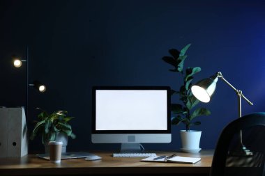 Ofisteki ahşap masa üzerinde modern bilgisayar, dizüstü bilgisayar ve kırtasiye malzemesi olan şık bir iş yeri.