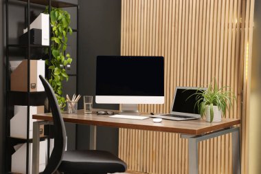 Modern bilgisayarlı ve ofisteki ahşap masada şık bir iş yeri.