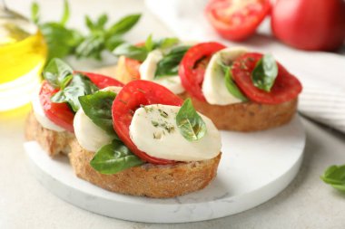 Mozarella peynirli lezzetli sandviçler, açık gri masada domates ve fesleğen, yakın plan.