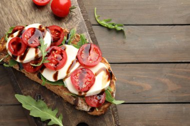 Mozzarella peynirli lezzetli sandviç, balzamik sos, domates ve roka, ahşap masa, üst manzara. Metin için boşluk