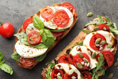 Mozarella peynirli lezzetli sandviçler ve gri masada domatesler.