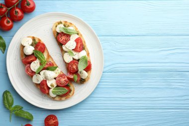 Mozarella peynirli, domatesli ve açık mavi ahşap masada fesleğenli lezzetli sandviçler. Metin için boşluk