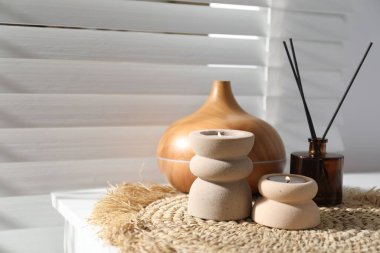 Kaplıca kompozisyonu yanan mumlar, aroma yağı yayıcı ve sazlık oda spreyi, kapalı masa, yakın çekim