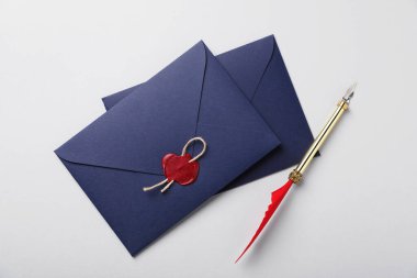 Beyaz zemin üzerinde balmumu mühür, sicim ve dolmakalem olan zarflar.