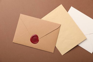 Kahverengi zemin üzerinde balmumu mühürü olan zarflar, düz uzanmış.