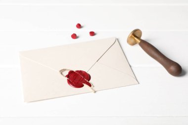 Balmumu mühürlü zarf ve beyaz ahşap masa üzerinde damga, yakın çekim