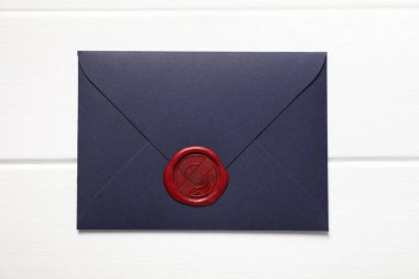 Üzerinde balmumu mühür olan zarf beyaz ahşap masa, üst manzara.