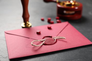 Balmumu mühürlü zarf, sicim ve damgalı siyah masa, yakın plan.