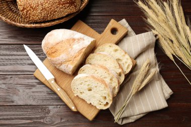Taze ekmek, bıçak ve buğday çivileri ahşap masada, düz yerde.