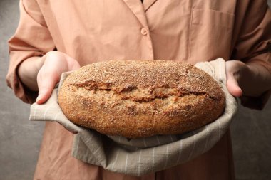 Gri arka planda taze ekmeği olan kadın, yakın plan.