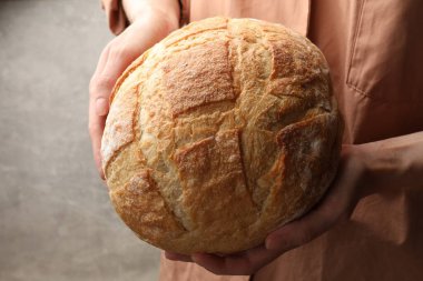 Gri arka planda taze ekmeği olan kadın, yakın plan.