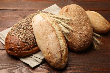 Somunlar taze ekmek ve buğday çivileri ahşap masada, yakın plan.