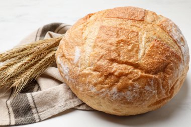 Beyaz mermer masada taze ekmek ve buğday çivileri, yakın plan.