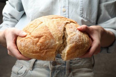 Bulanık arka planda bir somun taze ekmeği olan kadın, yakın plan