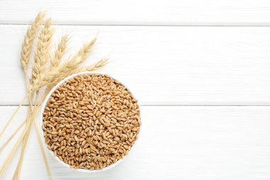 Kasede buğday taneleri, beyaz ahşap masada çiviler düz yerde. Metin için boşluk