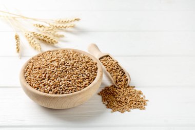 Kasede buğday taneleri, beyaz ahşap masada kepçeler ve çiviler, yakın plan. Metin için boşluk