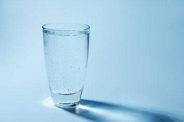 Açık mavi arka planda, bardakta soda tazeleniyor, yakın plan. Metin için boşluk