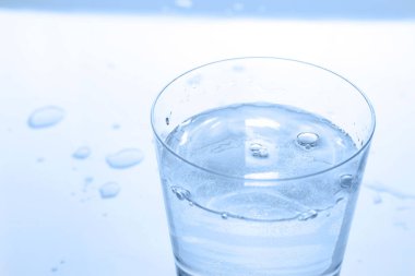 Bardaktaki soda suyunu beyaz masada damlalarla tazeliyor, yakın plan. Metin için boşluk