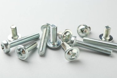 Açık gri arkaplanda birçok metal cıvata var, yakın plan. Donanım aracı