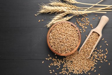 Kâsede buğday taneleri, siyah ahşap masada kepçeler ve çiviler düz yerde. Metin için boşluk