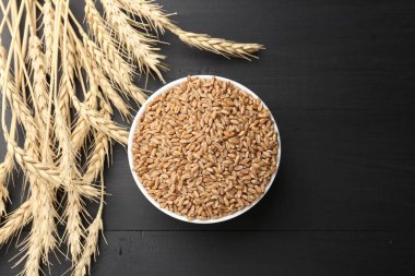 Kasede buğday taneleri ve siyah ahşap masada çivili çubuklar. Metin için boşluk