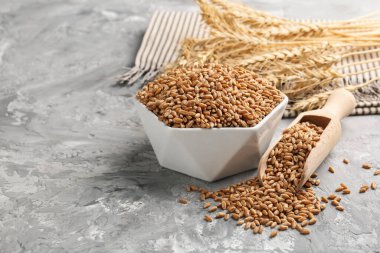 Kasede buğday taneleri, gri masada kepçeler ve çiviler, yakın plan. Metin için boşluk