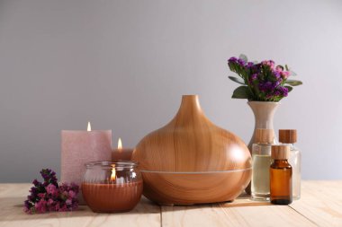 Çiçekli spa kompozisyonu ve ahşap masada yanan mumlar gri arka planda, yakın plan