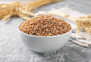 Kasede buğday taneleri ve gri masada çiviler, yakın plan.