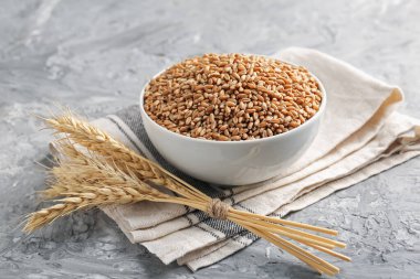 Kasede buğday taneleri ve gri masada çiviler, yakın plan.