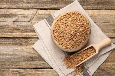 Kase içinde buğday taneleri ve tahta masaya kepçe, düz uzanmış. Metin için boşluk