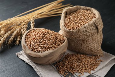 Kasede buğday taneleri, çuval bezi ve siyah masada çiviler.