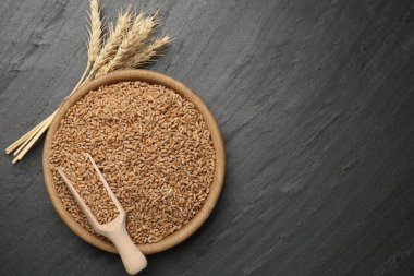 Kasede buğday taneleri, siyah masada kepçeler ve çiviler. Metin için boşluk