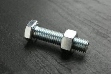 Metal cıvata ve ceviz siyah masada, yakın plan.