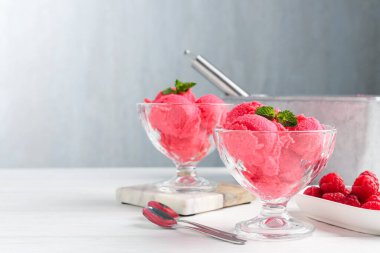 Tatlı kaselerinde naneli ahududu şerbeti, beyaz ahşap masada taze böğürtlen ve açık gri arka planda yakın plan. Metin için boşluk