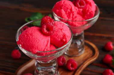 Tatlı kaselerinde nefis ahududu şerbeti ve ahşap masada taze böğürtlen, yakın plan.