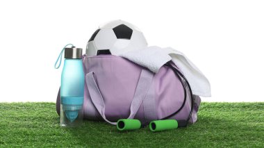 Spor malzemeleri, havlu ve şişe ile şık spor çantası beyaz arka planda yeşil çimenler üzerinde