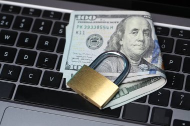 Siber güvenlik. Metal asma kilit ve dolar dizüstü bilgisayarda, yakın plan.