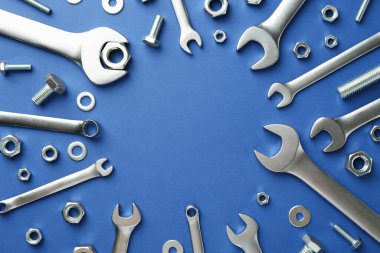 Metal anahtarlar, fındıklar ve cıvatalar mavi arka planda, düz yerde. Metin için boşluk