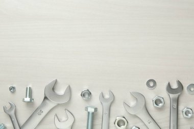 Metal anahtarlar, somunlar ve civatalar beyaz ahşap masada, düz yerde. Metin için boşluk