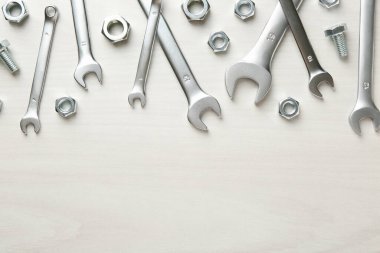 Metal anahtarlar, somunlar ve civatalar beyaz ahşap masada, düz yerde. Metin için boşluk