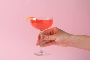 Pembe arka planda martini kokteyli olan kadın, yakın plan.