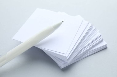 Açık gri arkaplan üzerine beyaz kalem ve not kağıtları, yakın plan