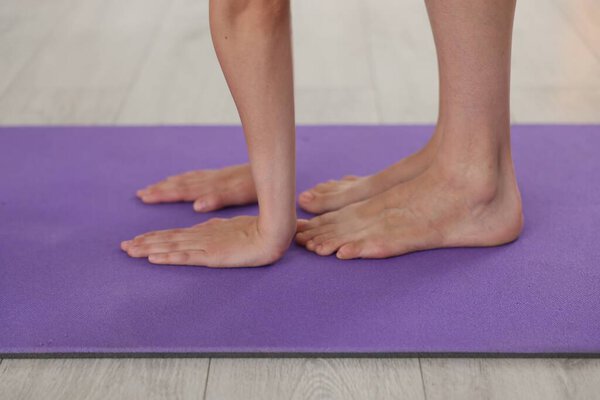 Woman stretching on mat at home, closeup