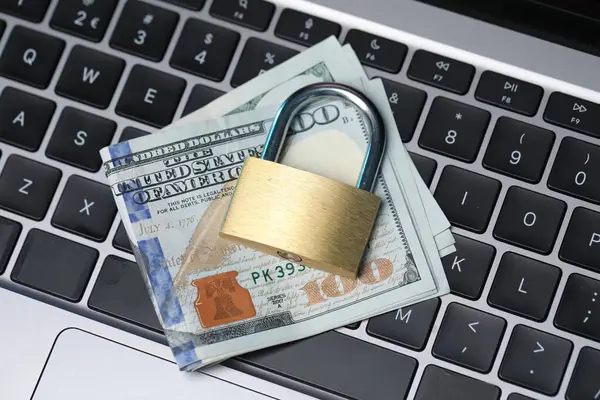Siber güvenlik. Metal asma kilit ve dolar dizüstü bilgisayarda, üst görünümde.