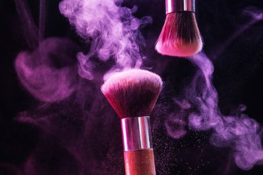 Renkli göz gölgeli makyaj fırçaları siyah arka planda neon ışıkları, yakın plan