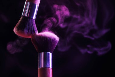 Siyah arka planda mor göz farlı makyaj fırçaları, yakın plan. Metin için boşluk