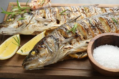 Gri masada biberiye ve limonla servis edilen lezzetli kavrulmuş deniz kabuğu balığı, yakın plan. Ev yapımı deniz ürünleri yemeği.