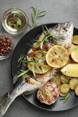 Gri masada patates, biberiye ve limonla servis edilen kızarmış dorado balığı. Ev yapımı deniz ürünleri yemeği.