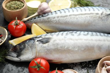 Siyah masada taze çiğ uskumrular ve baharatlar, yakın plan. Deniz ürünleri lezzetleri.